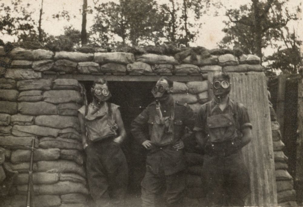 Soldiers pose with their small box respirators outside the entrance to their bunker, in the Ploegsteert sector, 1917/18.